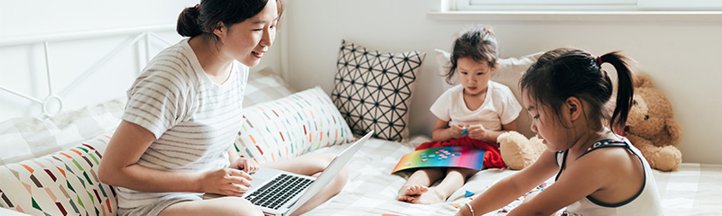 Young mother working at home while her two daughters play